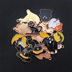 Close-up of enamel Halloween charms with ghost, bat, and witch hat designs on black background