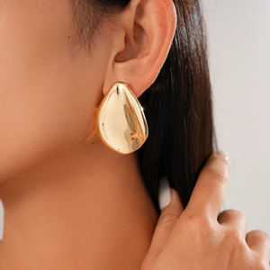 Irregular gold metal leaf earrings with shiny mirror finish on female model