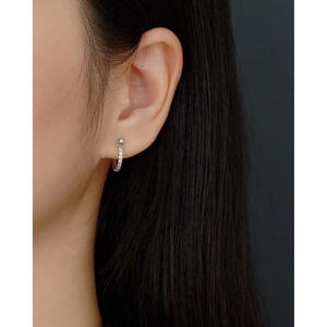 Macro shot of a 925 silver huggie earring with zircon stones worn on an earlobe
