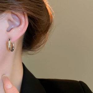 Close-up of minimalist silver hoop earrings with a polished finish on a model's ear