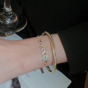 Close-up of gold-plated star and flower zircon bracelet set worn on a female wrist
