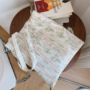 Dettaglio della borsa tote in cotone floreale con motivi blu su un tavolo di legno