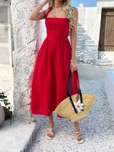 Detail of red halter-neck maxi dress with smocked waist shown in a vacation setting