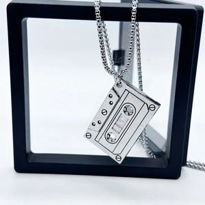 Retro cassette tape pendant necklace in silver metal, displayed in a black floating frame