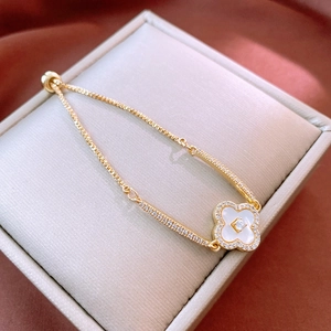 Close-up of gold-plated clover bracelet with white zircon inlay on jewelry box