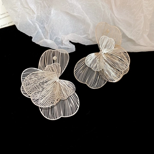 Détails des boucles d'oreilles fleurs argentées avec structures linéaires évidées et superposées