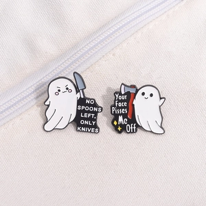 Detail of funny white ghost enamel pins featuring text with knives on canvas bag background