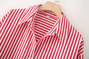 Close-up of a red and white striped poplin shirt with a turn-down collar on a wooden hanger