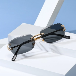 Detalle de gafas de sol cuadradas al aire con patillas doradas trenzadas de diseño