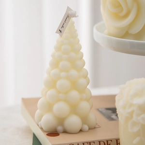 Close-up of a cream-white Christmas tree scented candle with bubble sphere texture on books