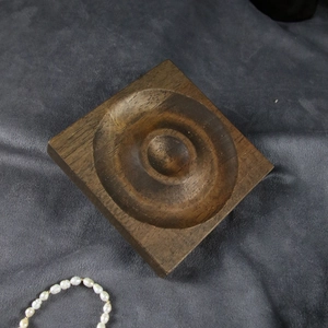 Macro detail of walnut wood jewelry display tray with smooth circular recessed grooves