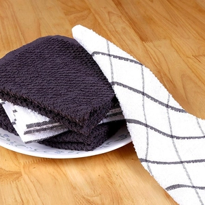 Detail of grey waffle weave and plaid cotton kitchen towels stacked on a ceramic plate