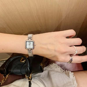 Close-up of a silver square quartz watch with a white shell dial and elegant metal bracelet