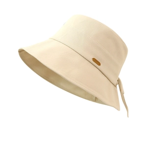 Chic beige cotton bucket hat with a stylish brown leather label and back bow detail