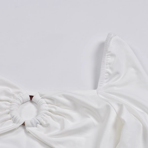 Nahaufnahme von weißem Strickkleid mit kreisförmiger Ring-Schnalle und Rippstoffstruktur