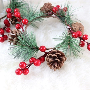 Weihnachtskranz mit grünen Kiefernadeln, echten Zapfen und roten Beeren auf weißem Fell
