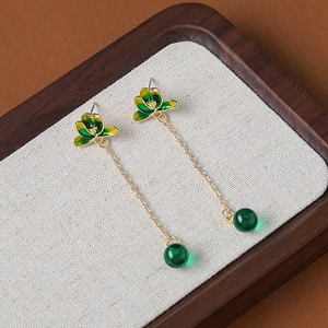 Vintage green enamel lotus heart earrings with long gold chains on linen background