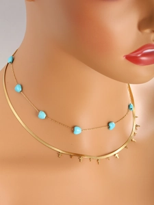 Detail of layered gold-plated 14K necklace with turquoise heart and cross charms