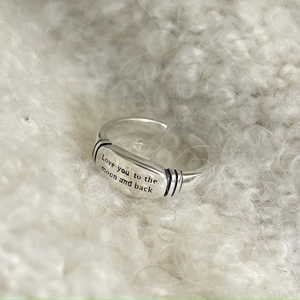 Detail of 925 sterling silver ring with engraved plate on soft white plush background