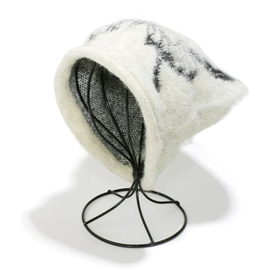 Detail of white chunky knit beanie with black patterns and warm fleece texture