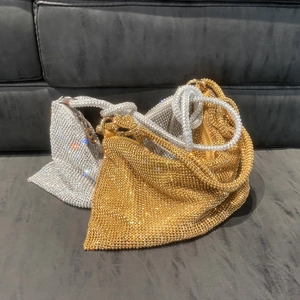 Close-up of sparkling rhinestone handbag featuring unique knotted handles in gold and silver