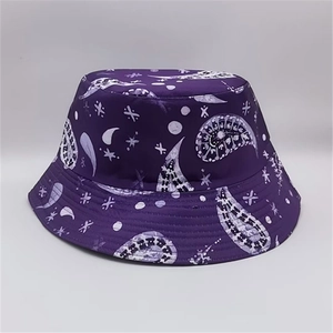 Detail of purple bucket hat with white paisley and moon patterns on a gray background