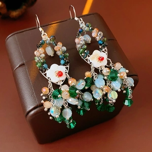 Detail von Boho-Ohrringen mit bunten Kristallperlen und weißer Muschelblumen-Deko