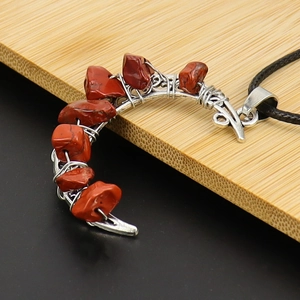 Detail of red jasper stone wrapped in silver wire on crescent moon pendant