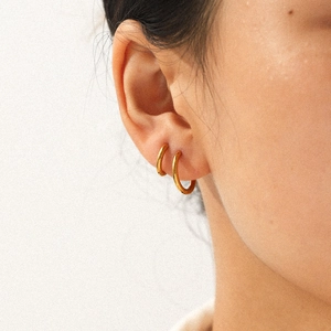 Gros plan de boucles d'oreilles créoles minimalistes en acier plaqué or 18k sur modèle