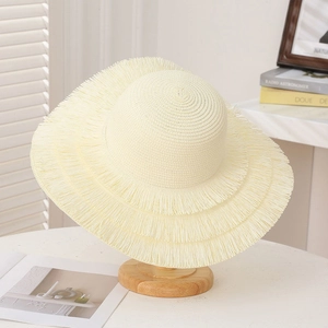 Detailed close-up of triple-layered fringe edges on a cream straw beach sun hat