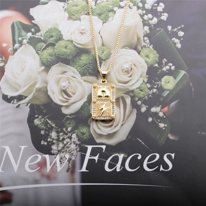 Detail view of gold rectangle pendant with lightning bolt relief and crystal border