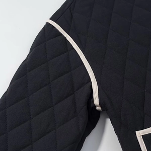 Macro view of black quilted jacket with diamond stitching and white contrast piping