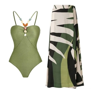 Detail of beaded halter neckline swimsuit and tropical leaf print wrap skirt