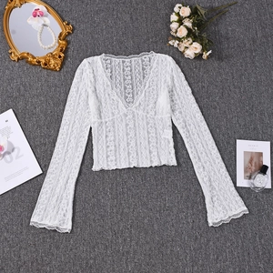 Flat lay of white sheer floral lace top with V-neck and flare sleeves on grey background