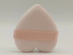Detail view of pink heart-shaped powder puff with soft velvet texture and finger strap