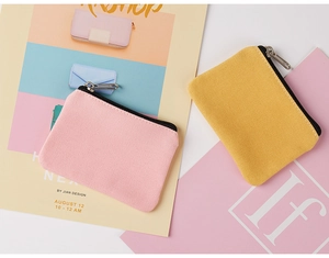 Flat lay of pink and yellow canvas coin purses with black zippers on artistic background