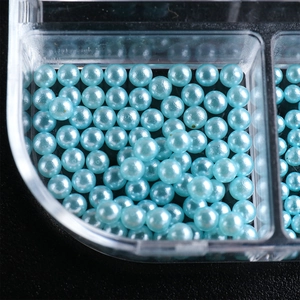 Macro shot of blue pearlescent round resin pearls for nail art in a plastic storage box