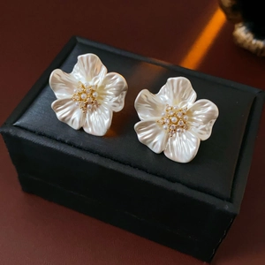 Close-up of gold plated flower stud earrings with pearls on a black jewelry box
