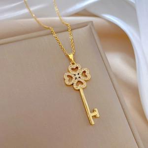 Close-up of gold clover key necklace with sparkling crystals on elegant beige jewelry box