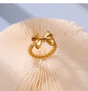 Dettaglio macro di un anello a fiocco dorato con trama a corda su base corallo