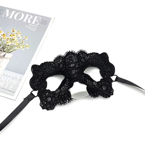 Detailed view of intricate black lace masquerade mask with silk ribbons on white background