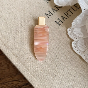 Detailed close-up of pink marble texture hair clip with elegant golden metal base