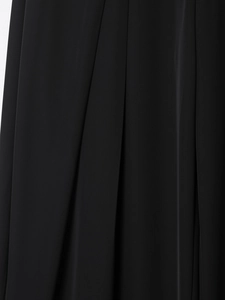 Close-up of black wide-leg trousers featuring fine pleats and premium draped fabric texture
