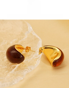 Detailed view of amber resin earrings with gold titanium steel on a rippled glass texture
