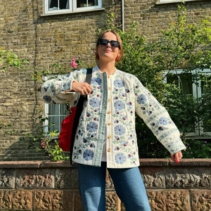 Floral quilted jacket for women featuring blue and red embroidery on a white background