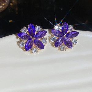 Macro view of flower stud earrings with purple marquise cut gems and white rhinestones