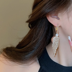 Close-up of elegant long tassel earrings with sparkling zircon crystals in gold setting