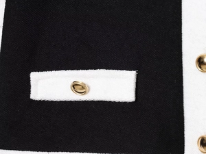 Détail de la texture en tweed contrasté et des boutons dorés sur la poche de la veste