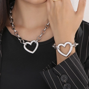 Close-up of chunky silver chain necklace and bracelet set with sparkling heart pendants