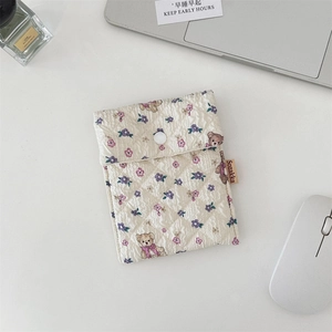 Gesteppte Tasche mit Bär und Blumenmuster auf weißem Tisch mit Laptop und Deko
